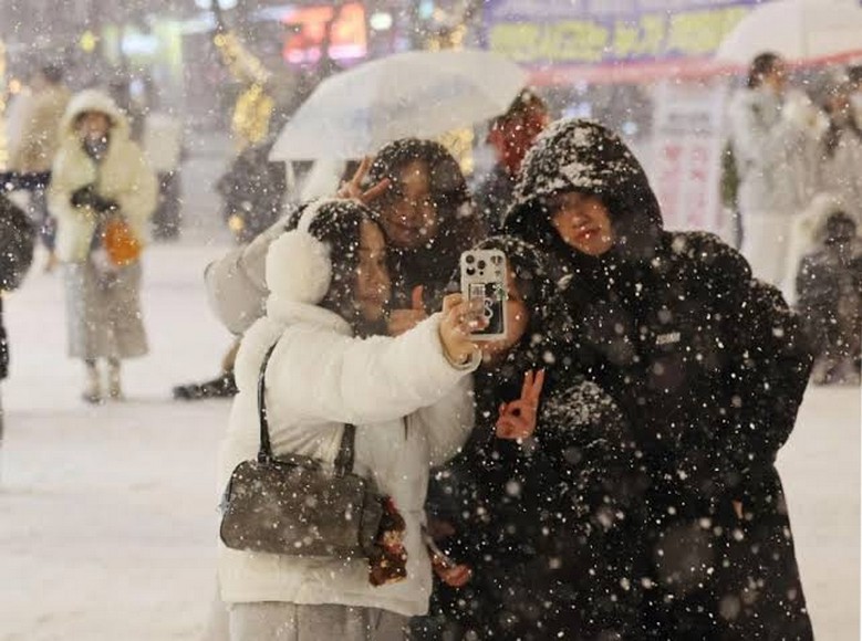 Du khách mặc áo phao dày đứng giữa tuyết rơi tại Seoul