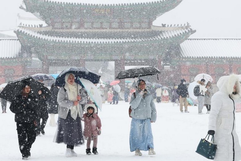 Du khách mặc áo phao dày giữa khung cảnh tuyết phủ ở Seoul