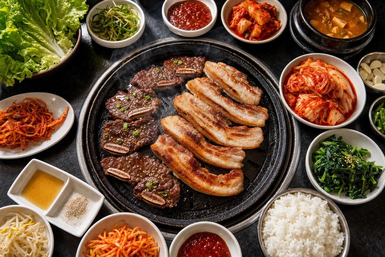 Mâm cơm Hàn Quốc với nhiều loại kim chi đặt cạnh thịt nướng và cơm trắng