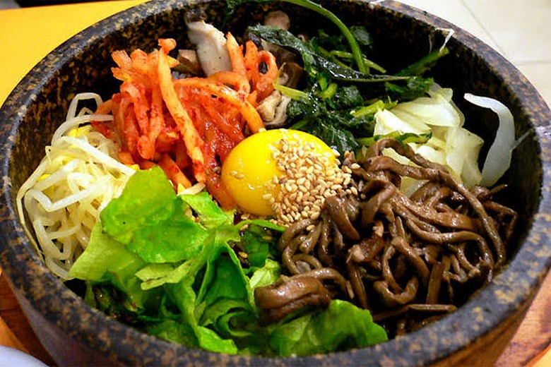 Một bát cơm trộn Bibimbap đầy màu sắc với rau củ, trứng lòng đào và tương ớt ở giữa