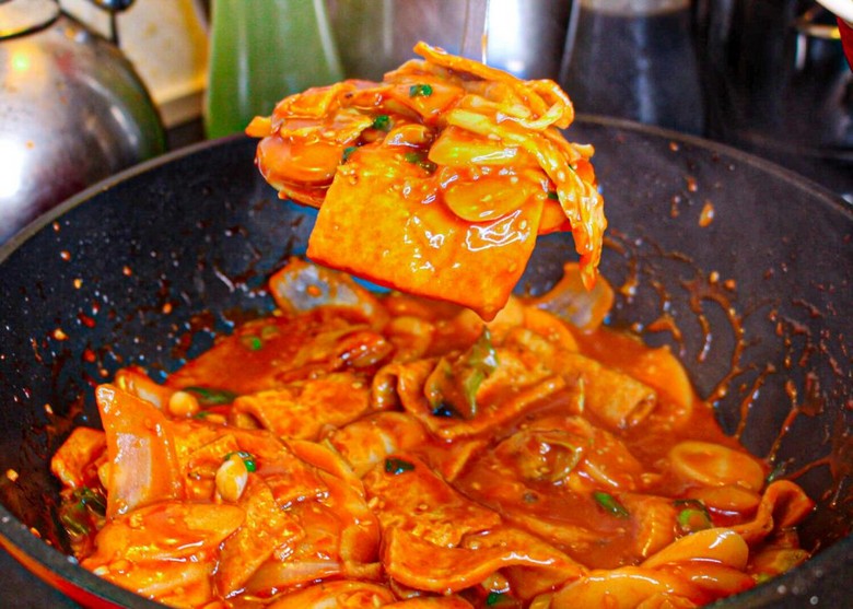 Một phần tteokbokki đỏ óng với bánh gạo, chả cá và trứng tại quầy vỉa hè
