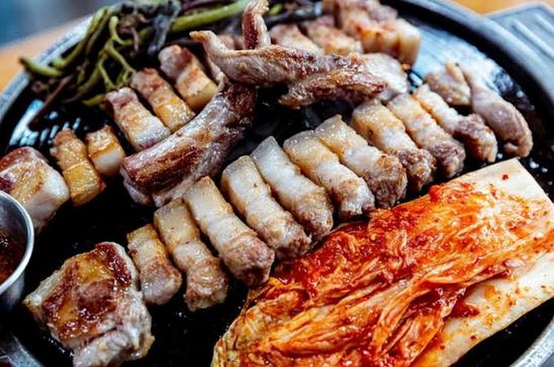 Miếng kim chi nướng cháy cạnh trên vỉ cùng thịt ba chỉ samgyeopsal