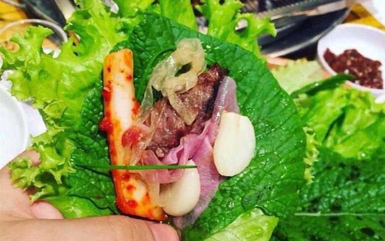Miếng thịt ba chỉ nướng được cuốn trong lá xà lách cùng tỏi và tương ssamjang