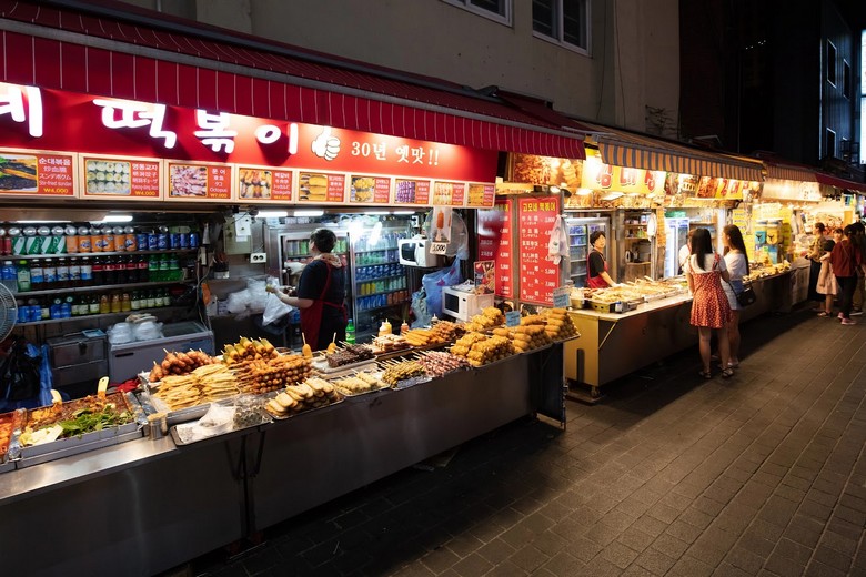 Phố ăn vặt Myeongdong buổi tối với các quầy đồ ăn đường phố sáng đèn