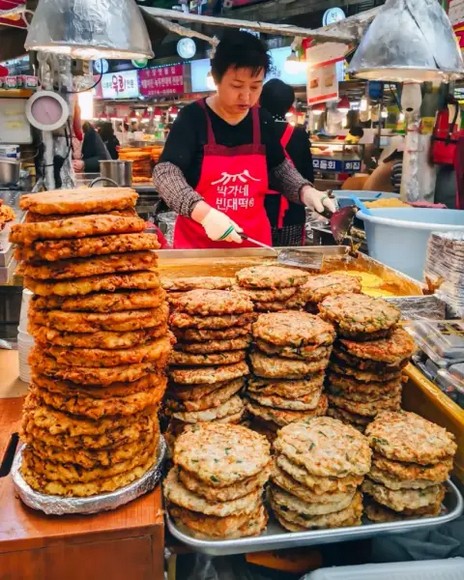 Quầy hàng bindaetteok đang chiên bánh vàng giòn tại chợ Gwangjang