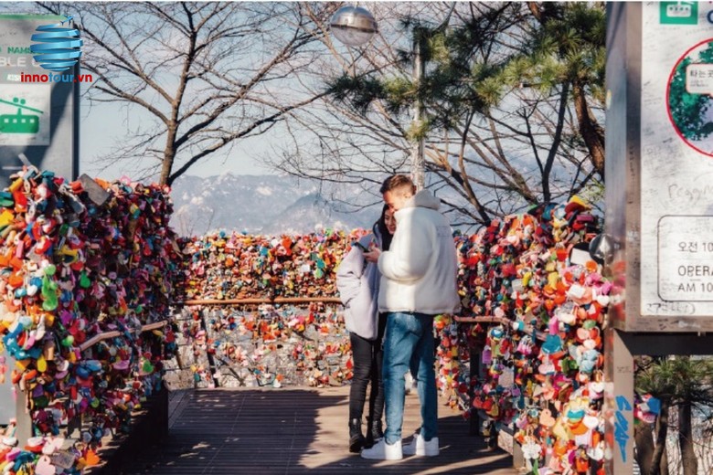 Cặp đôi mặc áo ấm chụp ảnh tại tháp Namsan mùa đông